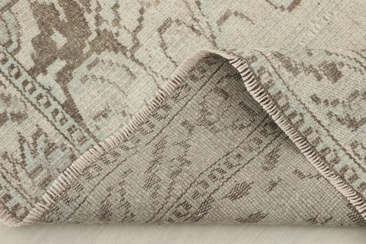 View of a folded corner of the rug, showing the wool pile and cotton foundation