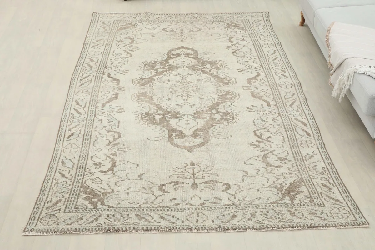 Overhead view of the ivory and tan vintage rug laid out, showing its full design