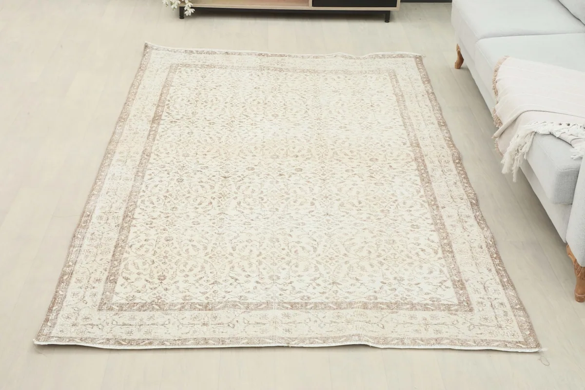 Overhead view of the ivory and beige floral vintage rug in a room, next to a light-colored sofa