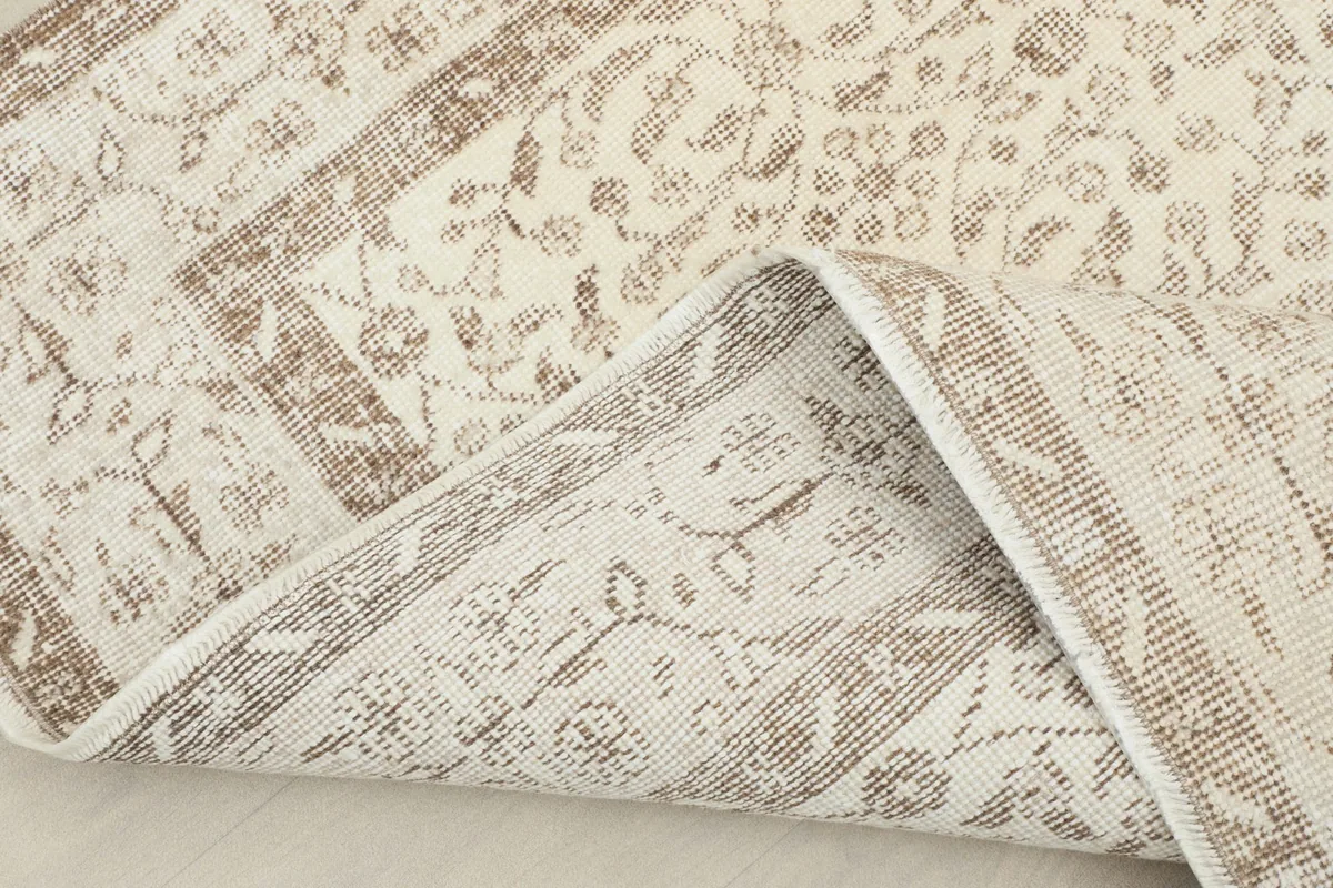 Corner of the rug folded back to reveal the hand-knotted cotton foundation and reverse side
