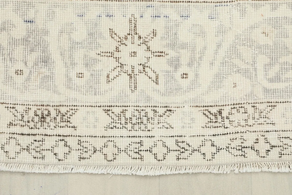 Detail of the rug's border, showing geometric patterns and the short fringe along the edge.