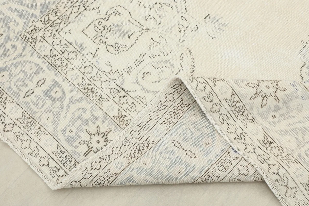 View of the rug's folded edge, showing the cotton foundation and the reverse side of the hand-knotted construction.