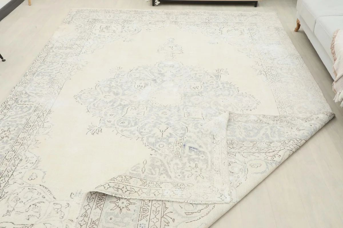 The large rug with a corner folded back, revealing the backing and the density of the wool pile.