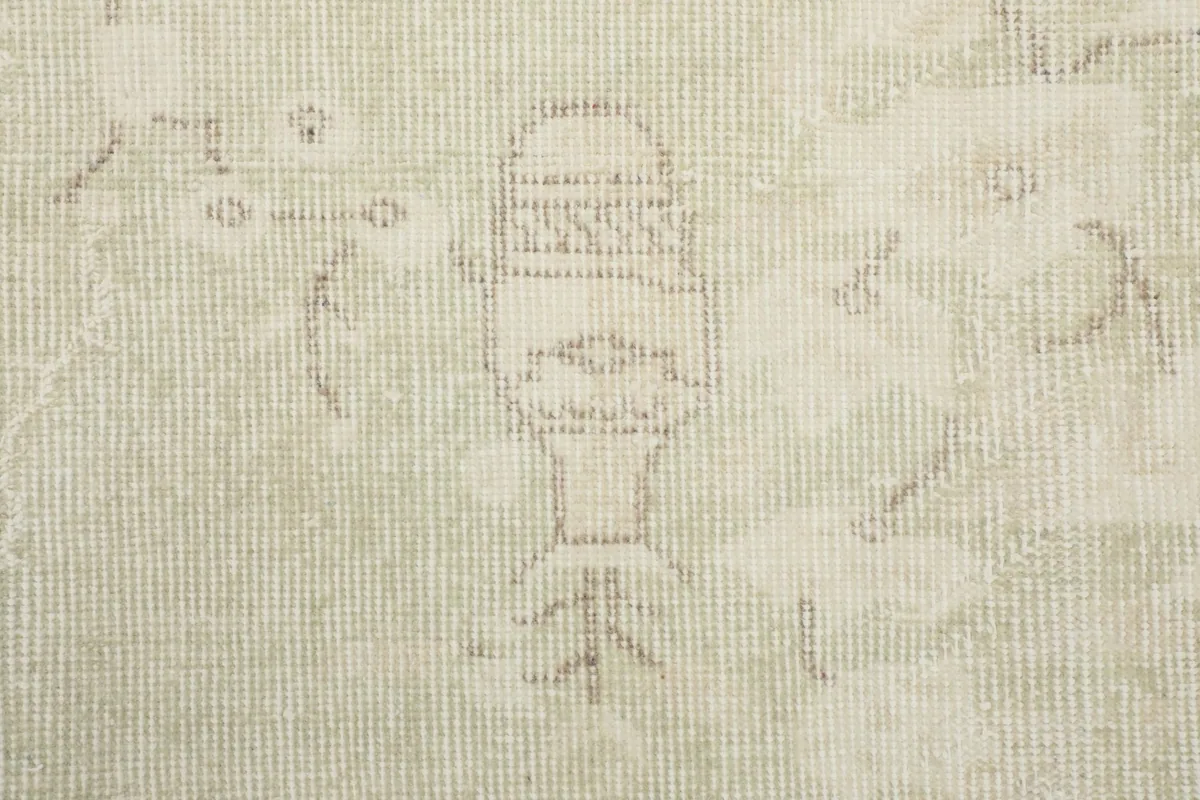 Close-up detail of a faded geometric motif and the hand-knotted wool pile