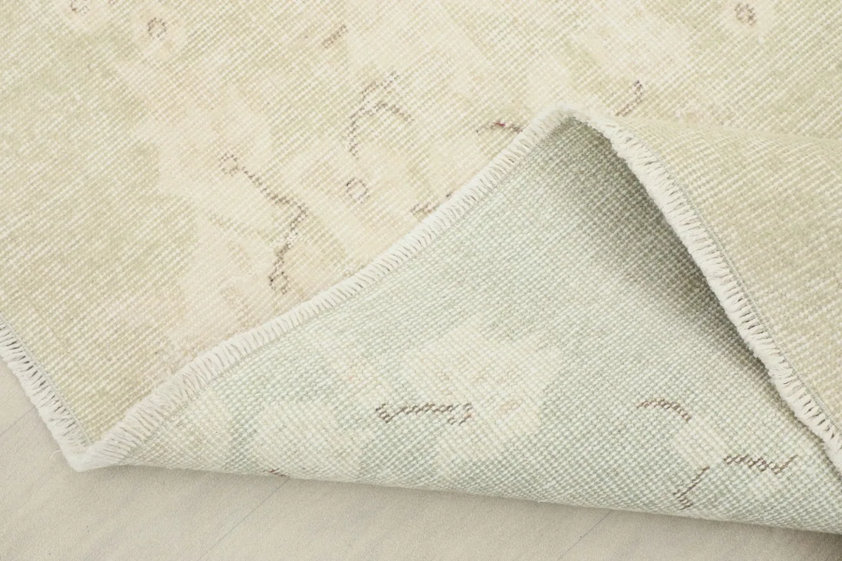Corner of the rug folded back to show the cotton foundation and knotting