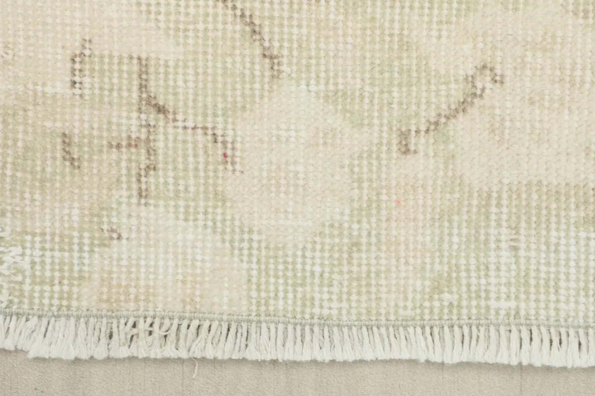 Detail of the short, hand-finished fringes and the edge of the cream rug