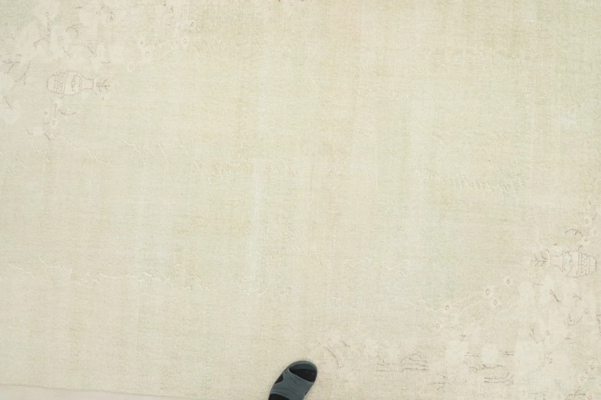 Overhead view of the rug with a foot for scale, showing the low pile texture
