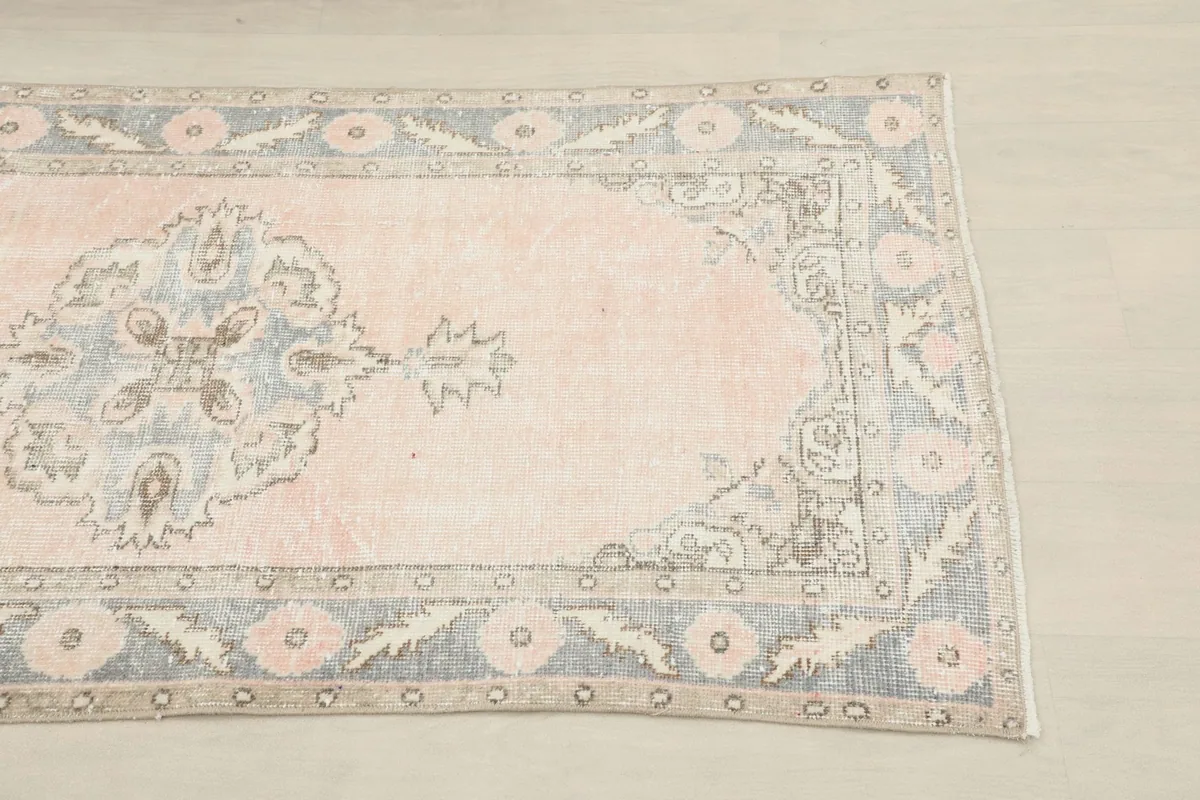 Close-up of the rug's end, highlighting the rose field and gray border with floral details.