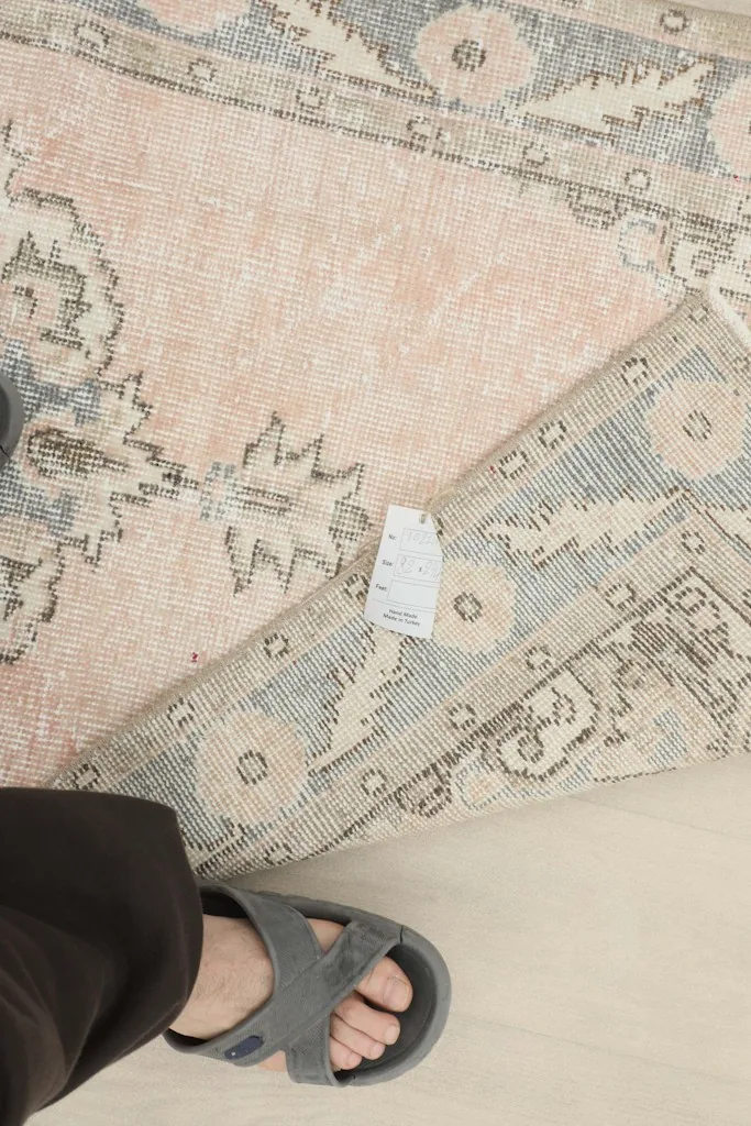 View of the rug's underside with a tag, showing the hand-knotted cotton foundation and wool knots.