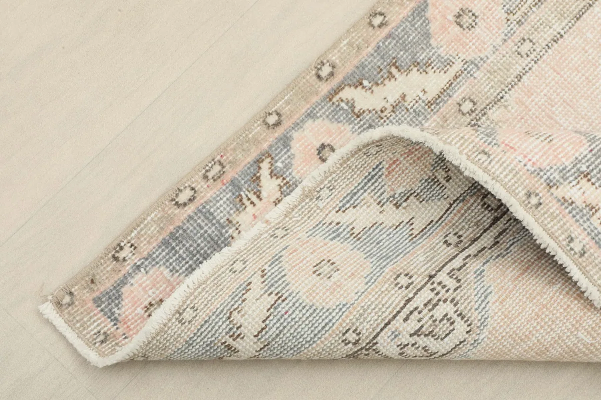 Corner of the rug folded back, revealing the wool pile and cotton foundation from the underside.