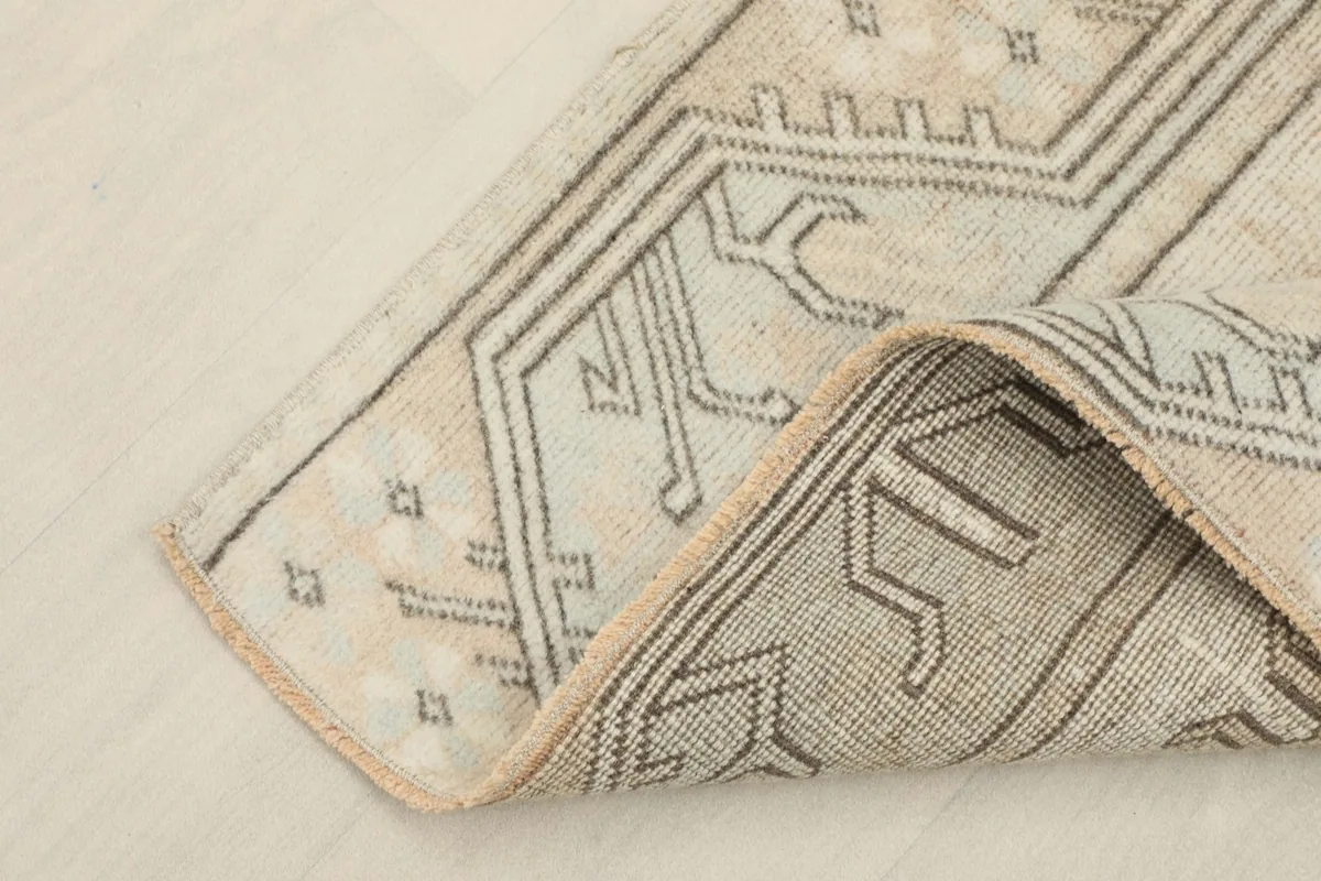 Close-up of the rug's folded corner, revealing the cotton foundation and knotting