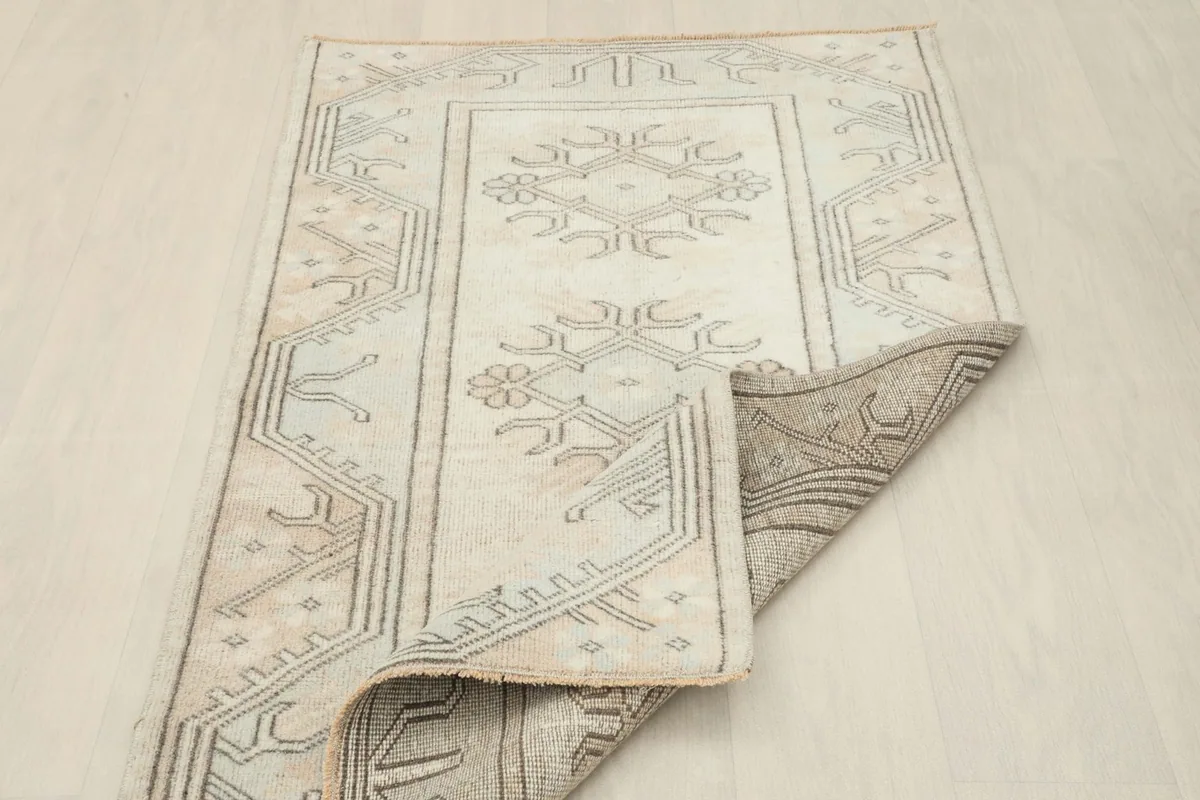 Angled view with a corner folded to show the back of the hand-knotted rug