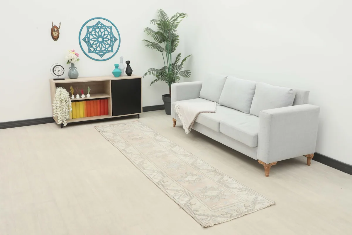 Vintage runner rug in a room setting, placed in front of a light gray sofa and a cabinet