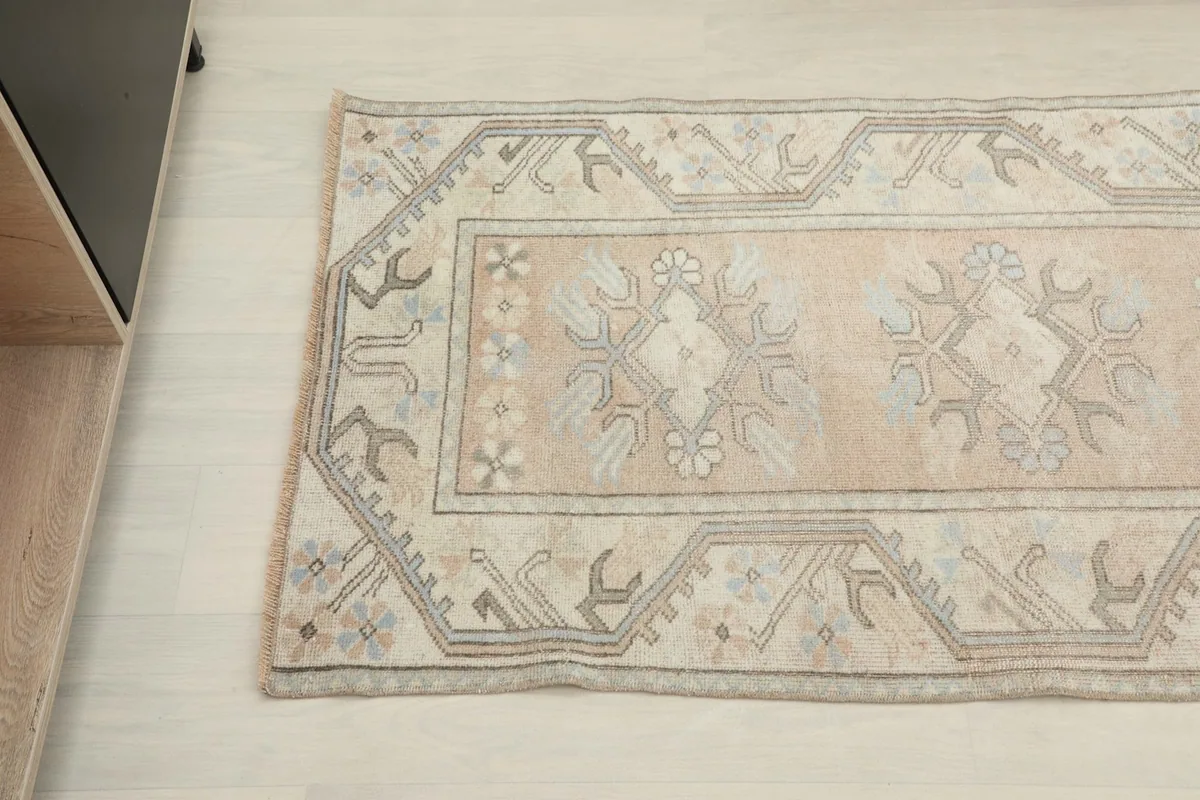 Detailed view of the rug's pattern and border, showing the subtle color variations and wear