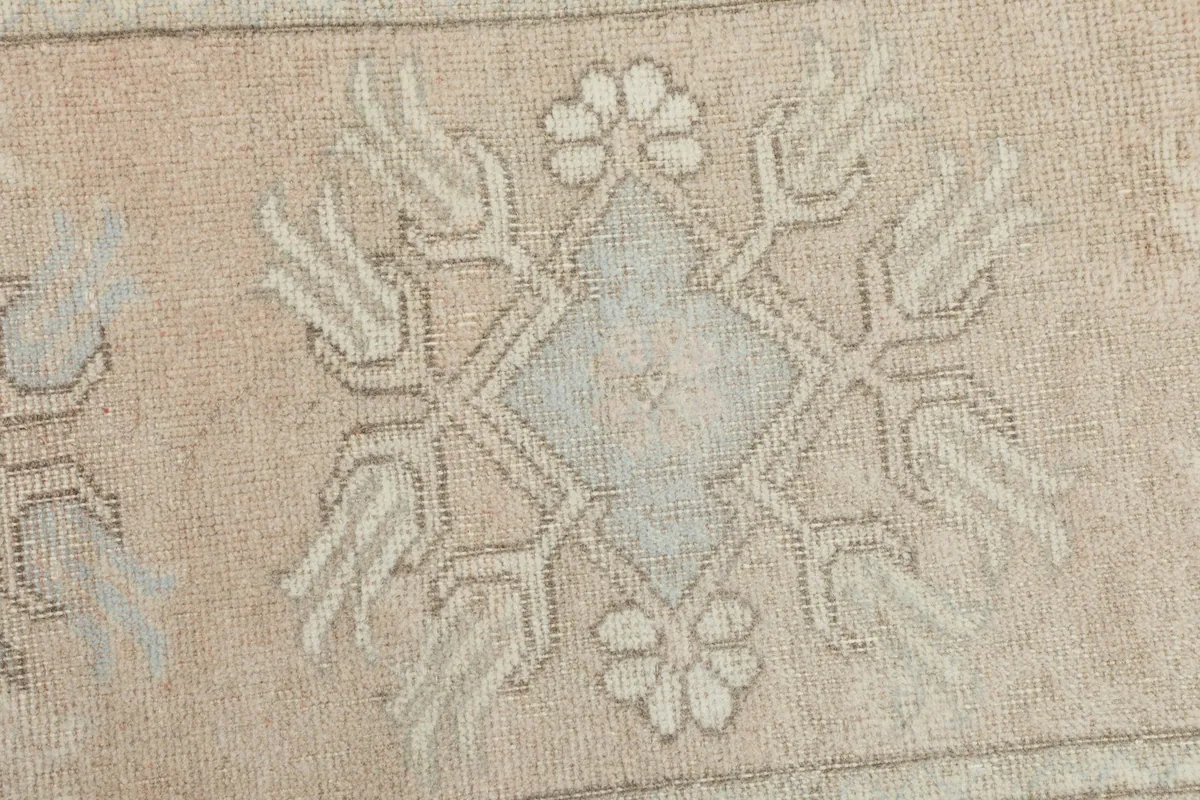 Extreme close-up of a central geometric motif in beige, gray, and blue, showing knot detail