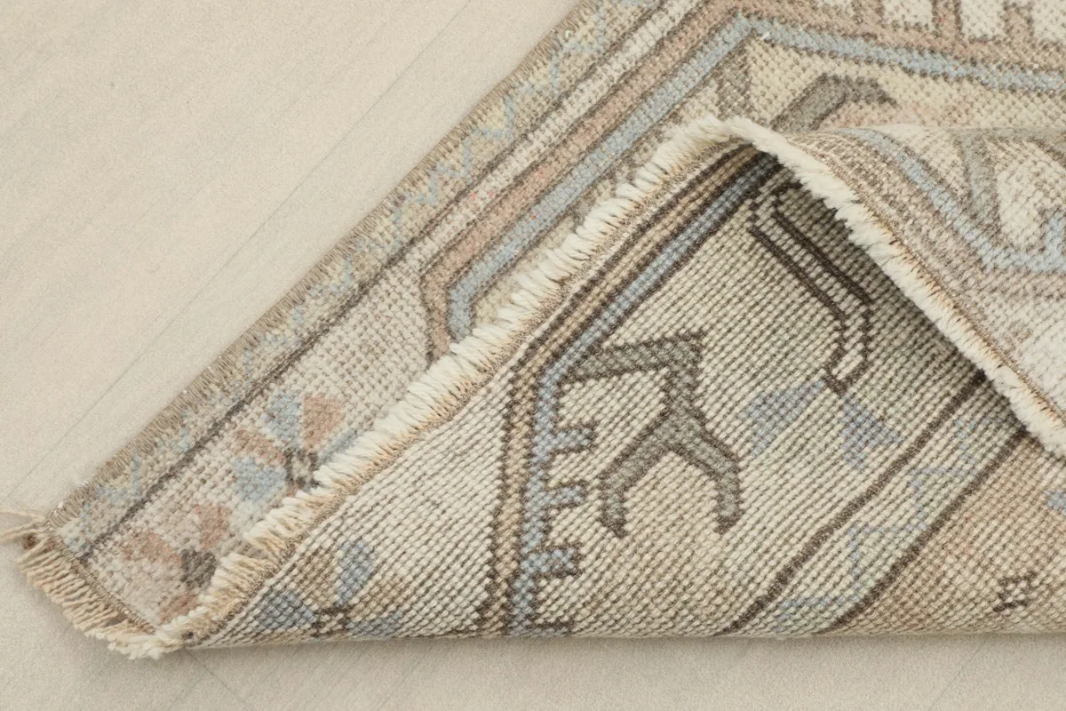 Folded corner of the rug showing the reverse side with visible knots and cotton foundation