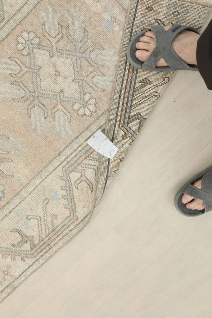 Overhead view of the rug with feet in sandals, providing a sense of scale and texture