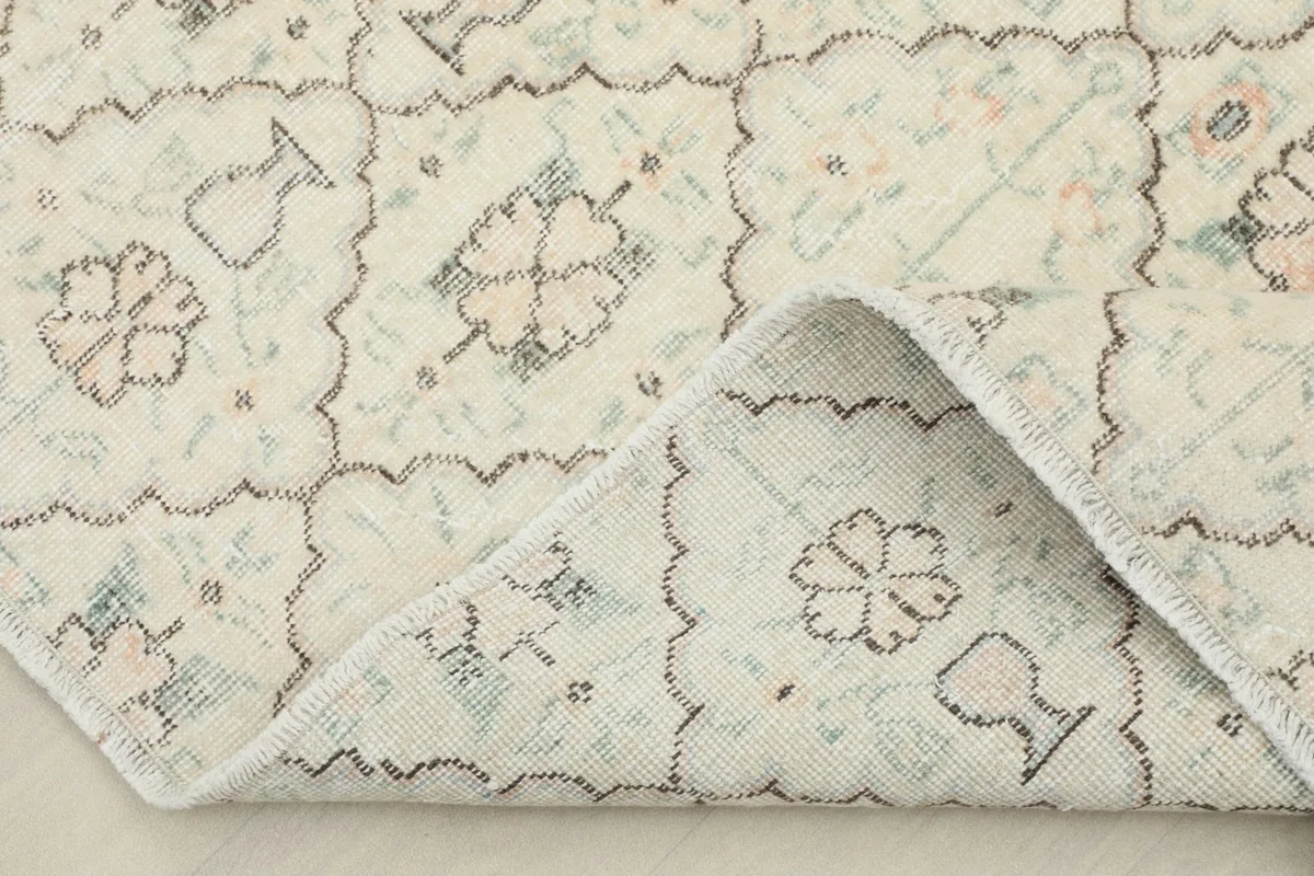 Corner of the rug folded back, revealing the hand-knotted cotton foundation