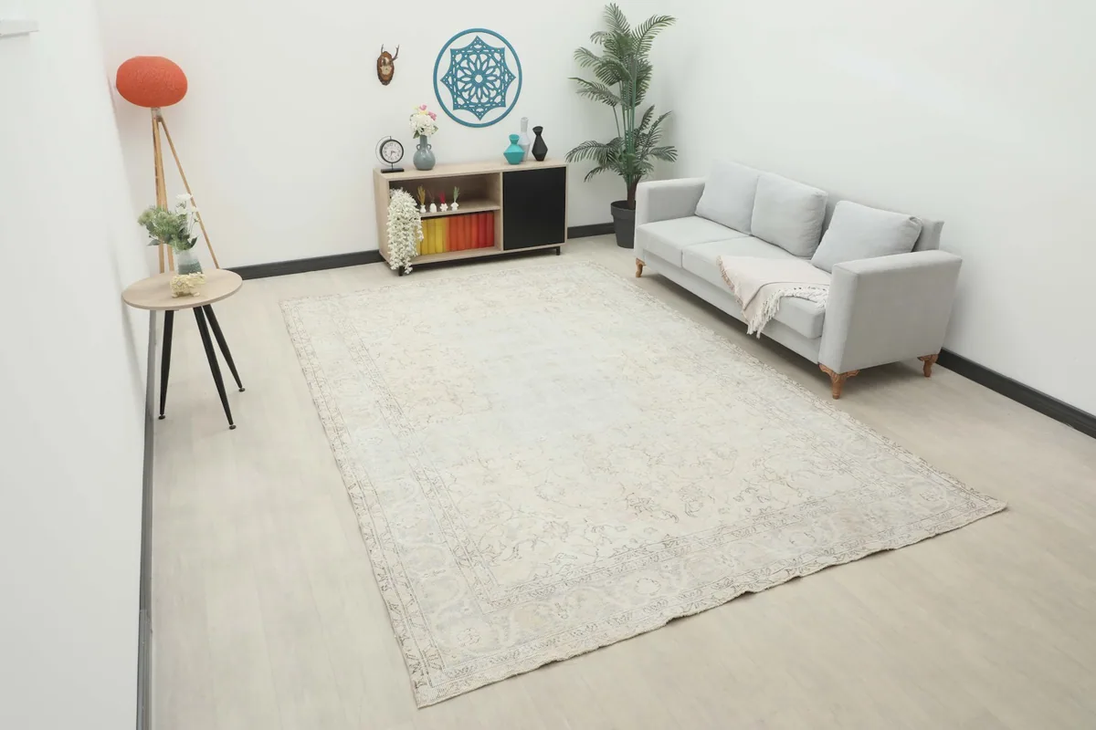 Large ivory vintage rug displayed in a modern living room setting with a sofa and side table