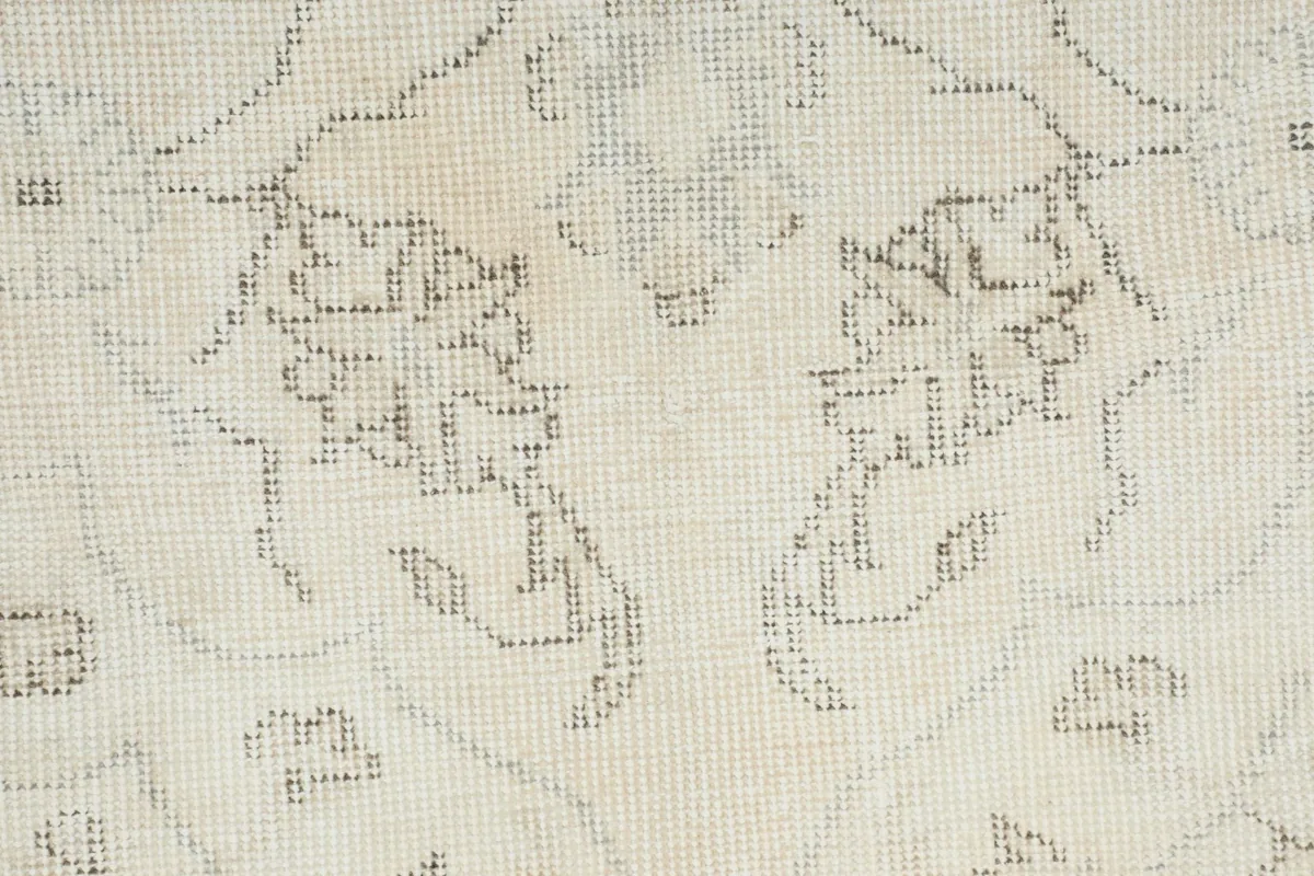 Close-up detail of the hand-knotted wool pile and subtle gray floral patterns