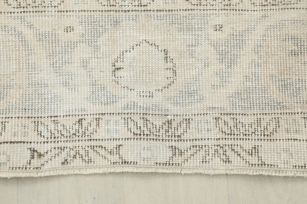 Detailed view of the rug's border, showcasing the hand-knotted texture and faded design