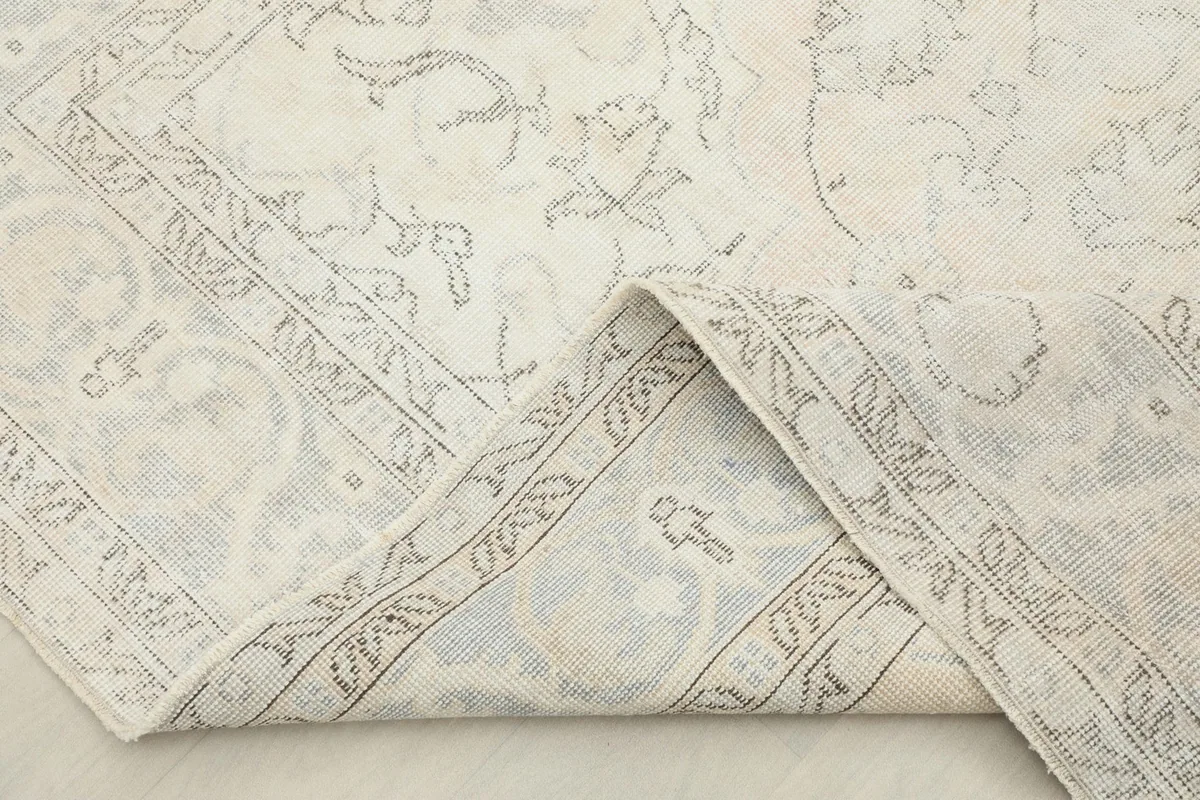 Folded corner of the rug, revealing the cotton foundation and the reverse side's pattern