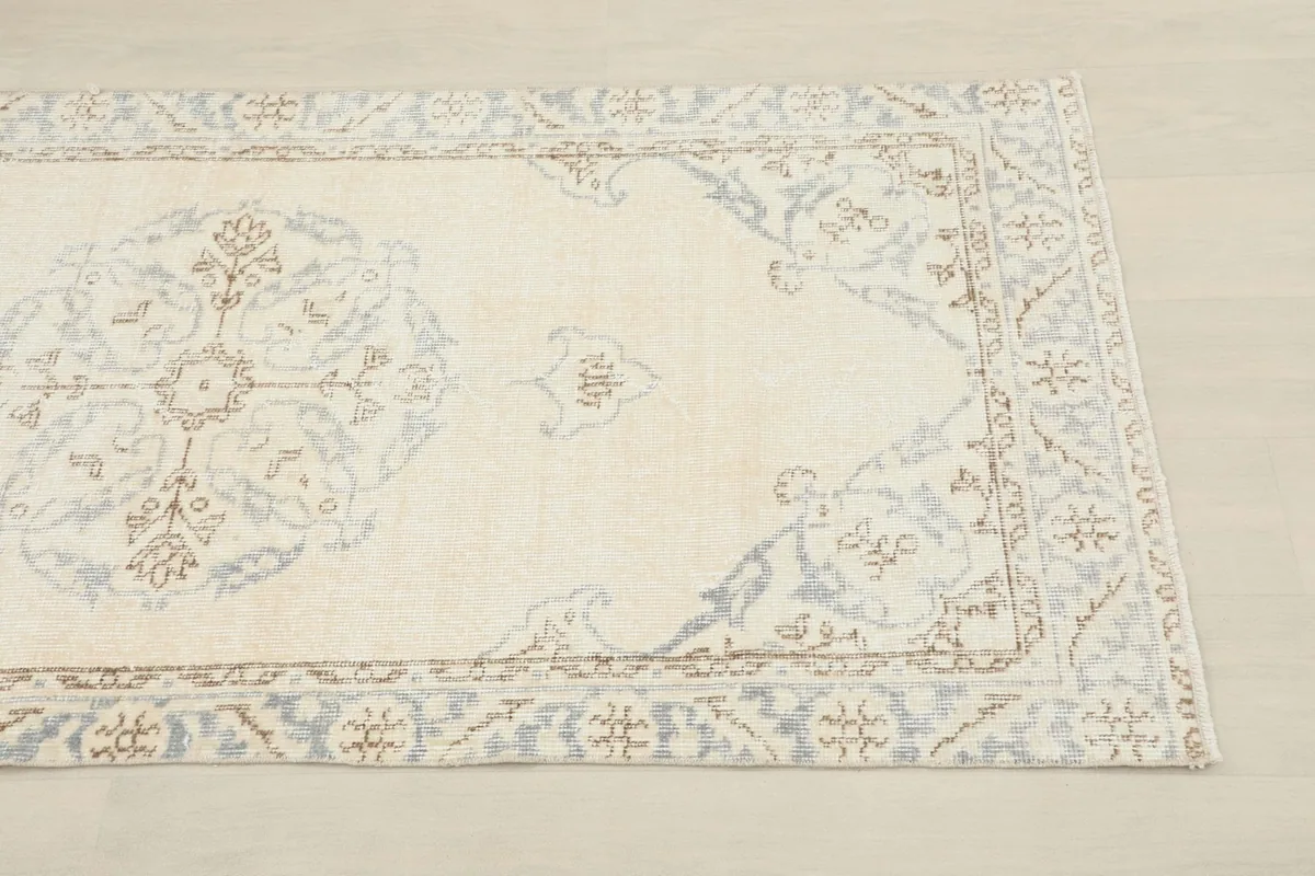 Close-up of the rug's end, highlighting the cream and gray border pattern and field detail.