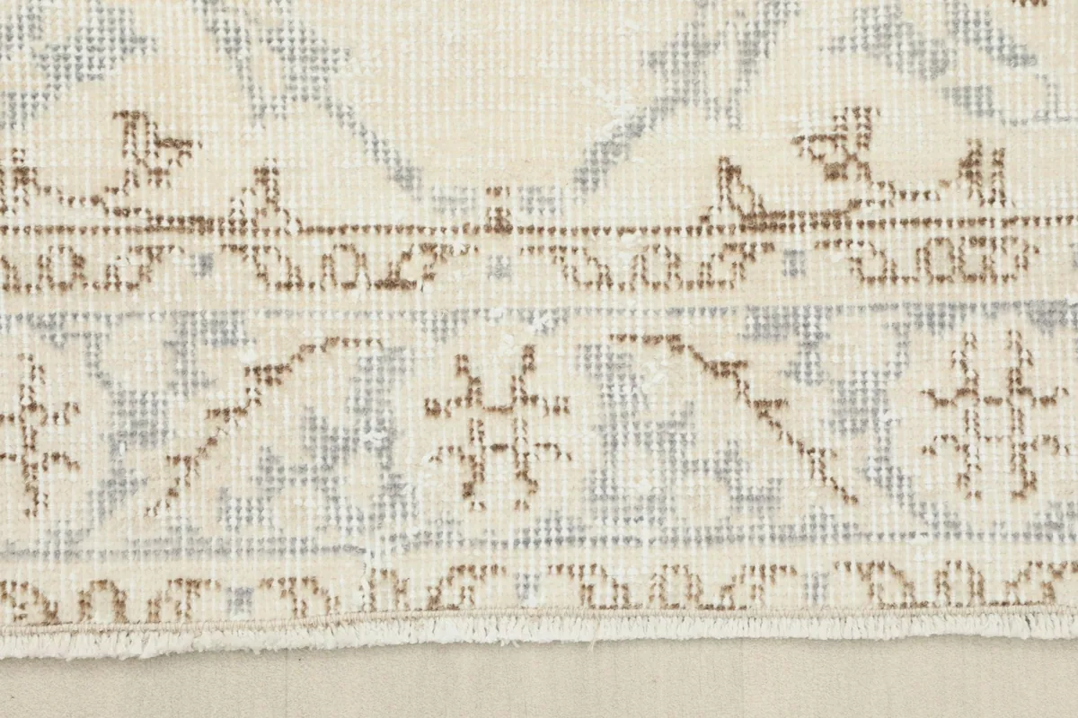 Detail of the rug's edge, showing the low pile, border pattern, and short, natural fringes.