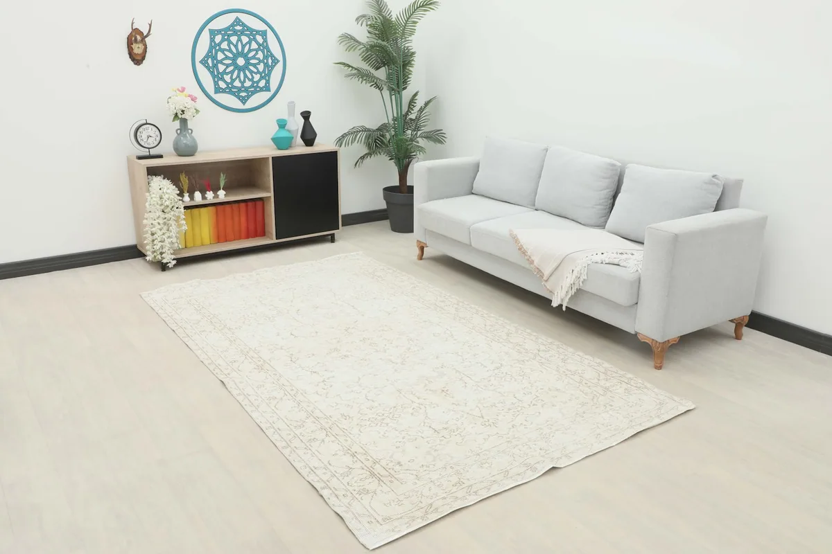 Ivory vintage rug displayed in a modern living room setting with a light gray sofa and wooden cabinet.