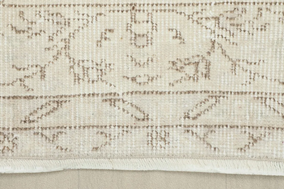 Detail of the rug's border design and the short, natural fringe at the edge.