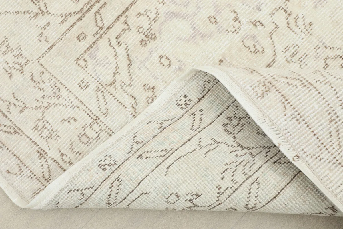 Corner of the rug folded back, showing the wool pile and cotton foundation construction.