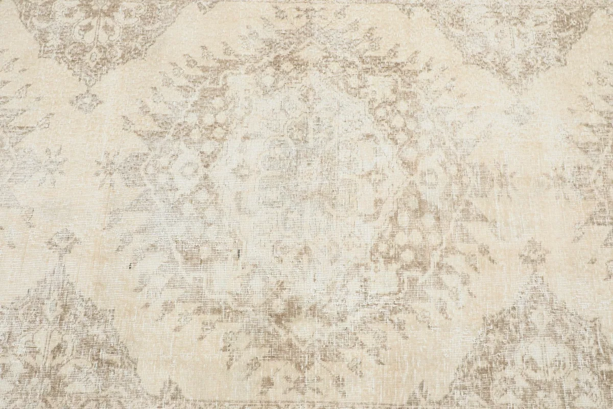 Close-up of the central medallion design on the ivory and beige vintage rug