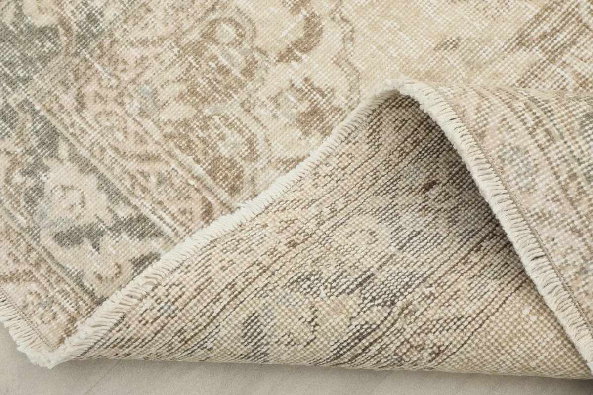 Corner of the rug folded to show the hand-knotted wool pile on a cotton foundation