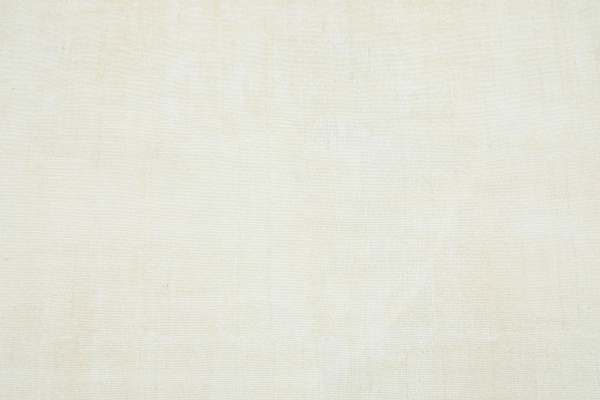 Detailed view of the cream rug's surface, emphasizing the hand-knotted wool pile and its soft, solid color.