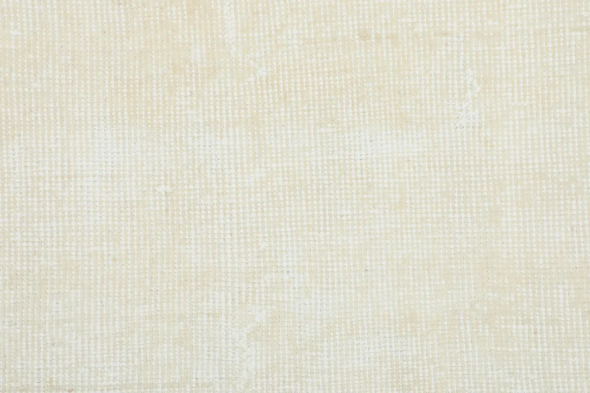 Close-up of the rug's low wool pile, showing the tight knotting and texture of the cream fibers.