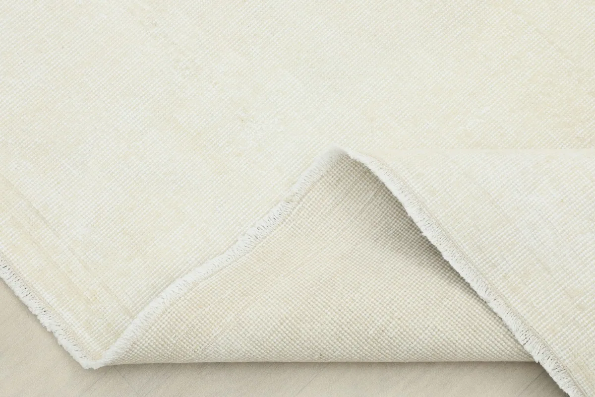 View of the back of the rug, folded to show the cotton foundation and the reverse side of the hand-knotting.