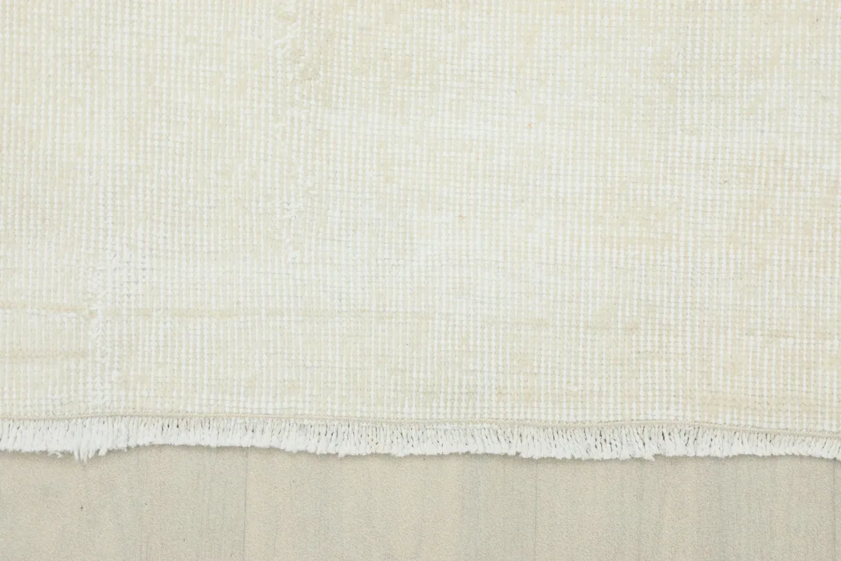 Detail of the rug's natural fringe and the edge of the hand-knotted cream wool pile.
