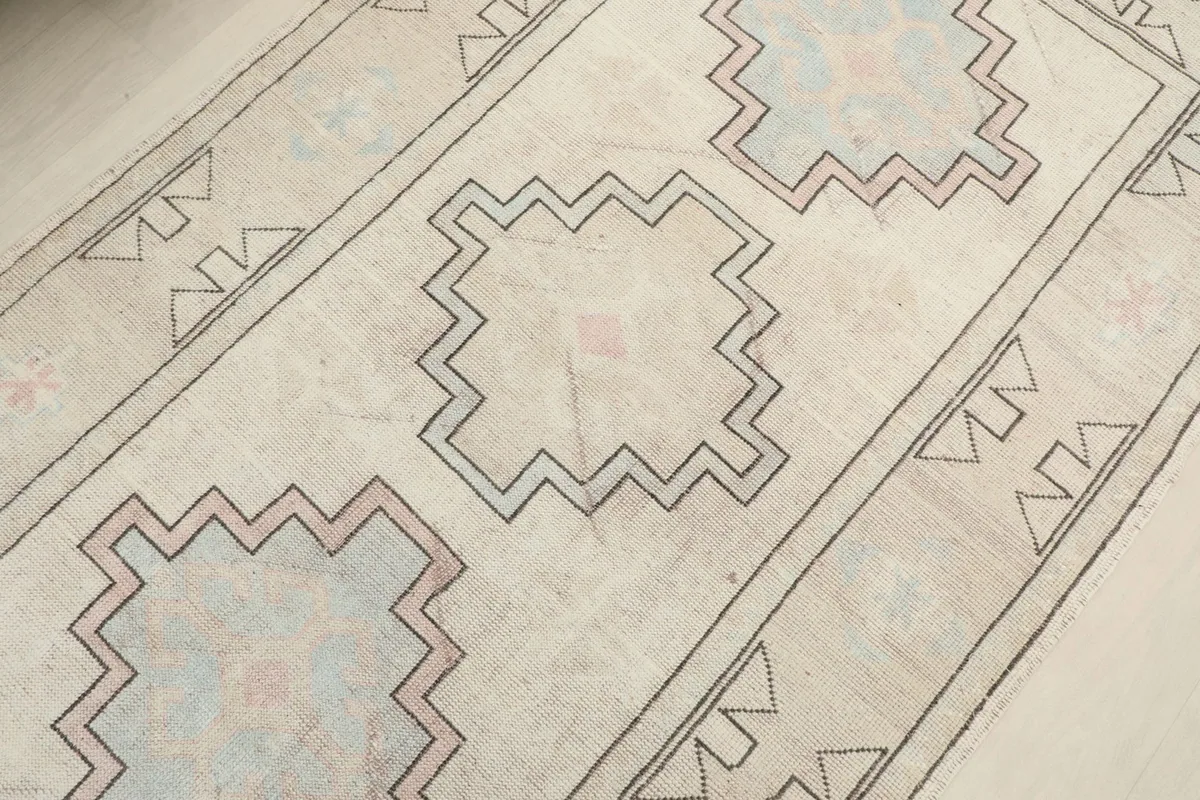Detailed view of the central geometric motifs in ivory, beige, pink, and blue tones.