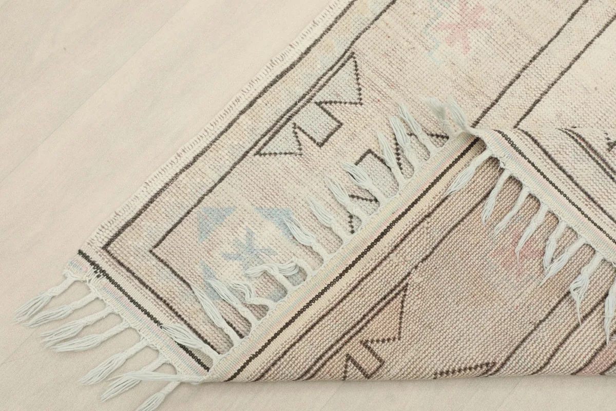 View of the rug folded back, showing the back of the hand-knotted wool on cotton foundation.