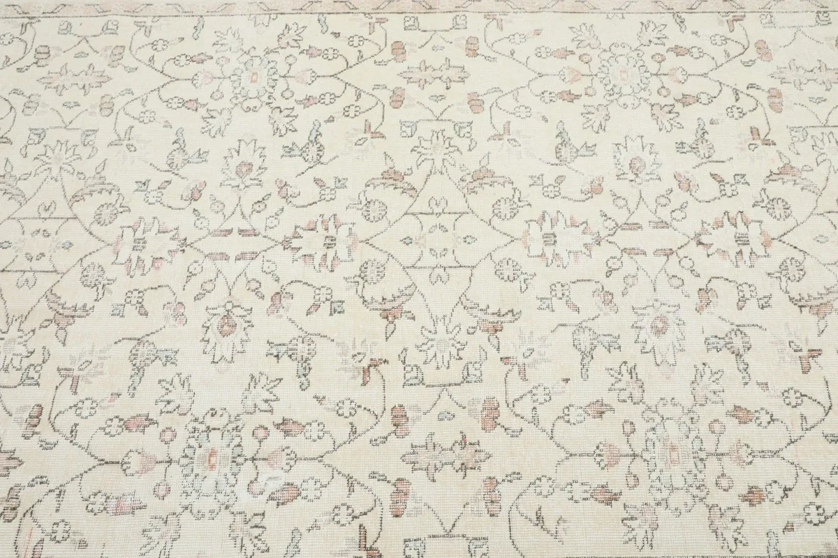 Detailed view of the central floral and geometric motifs on the rug's ivory background.