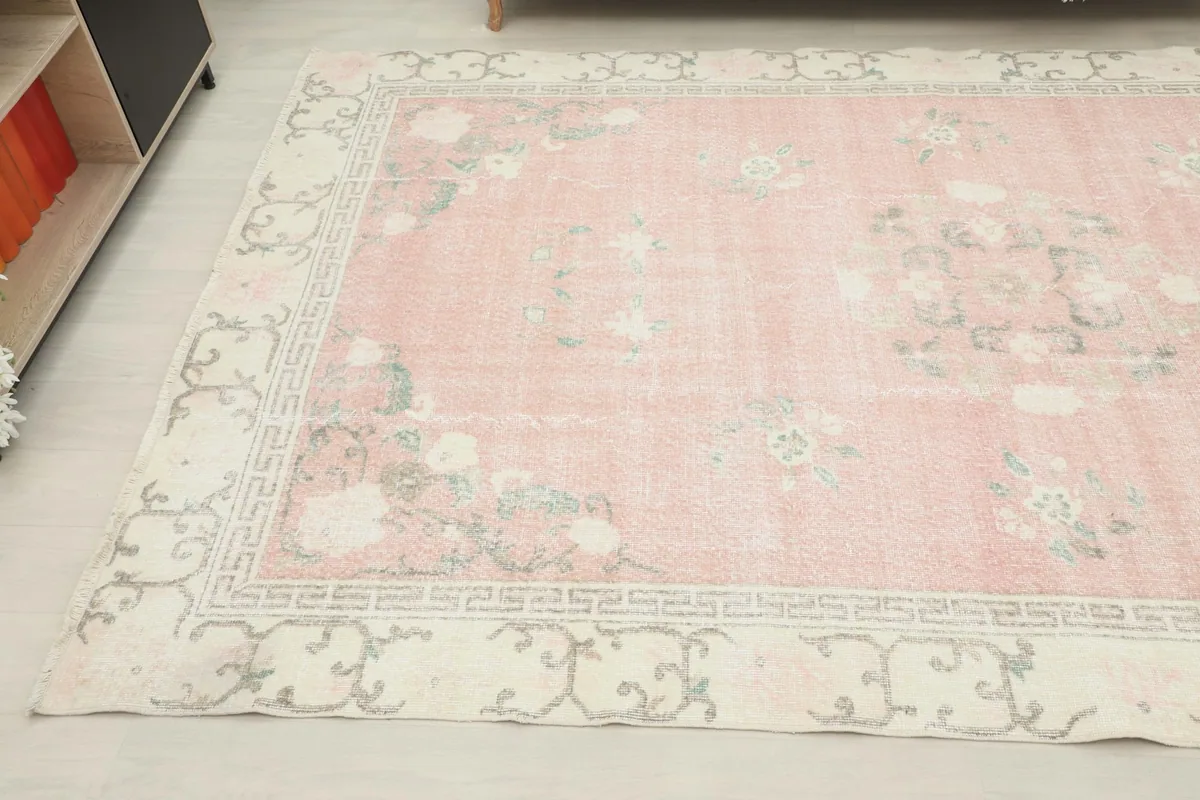 Corner view of the pink rug showing its placement in a room, emphasizing the distressed texture.