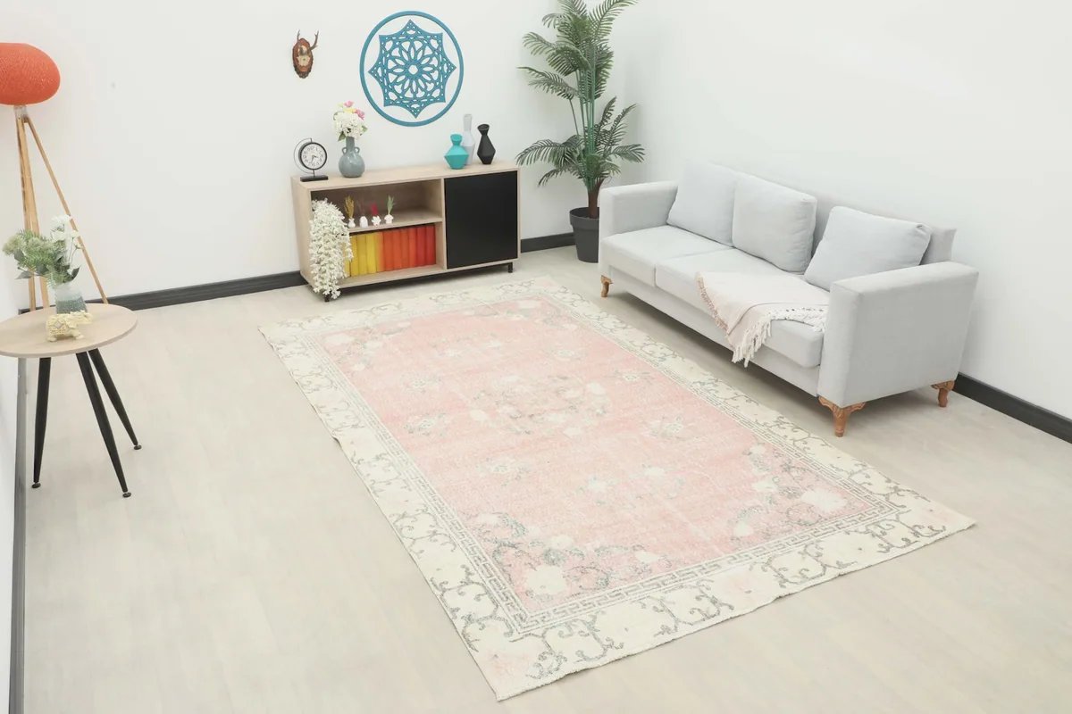 Vintage pink rug displayed in a bright living room setting with a light gray sofa.