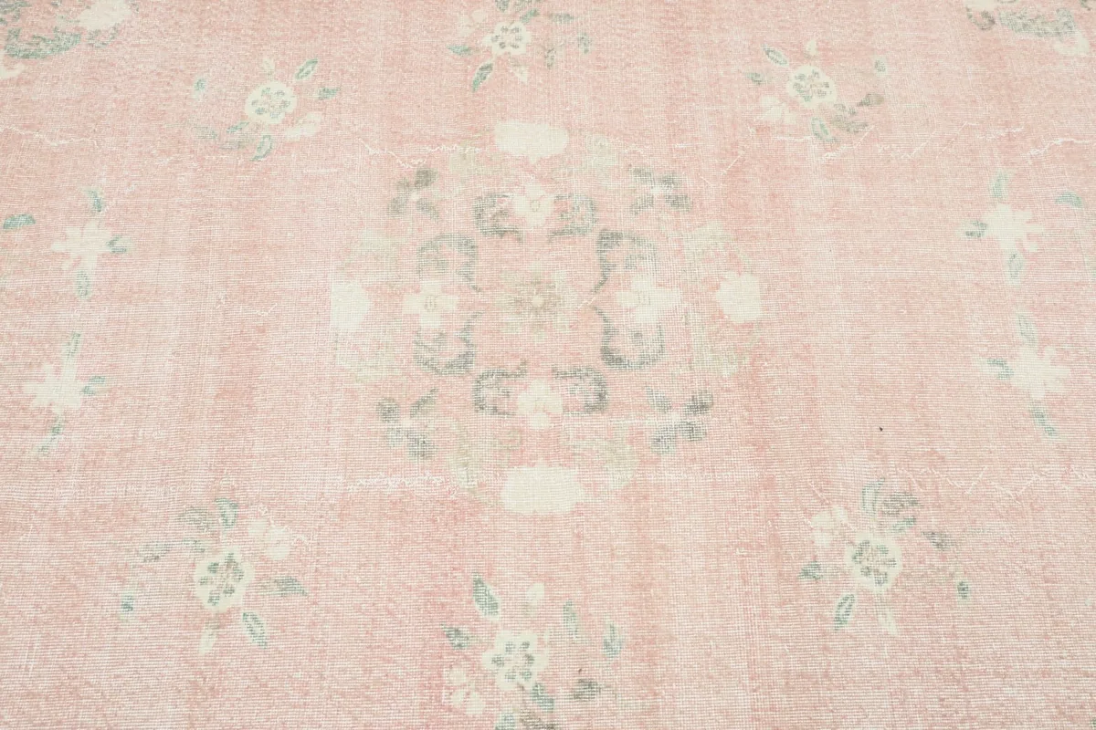 Close-up of the central area of the rug, revealing faded floral motifs and subtle color variations.