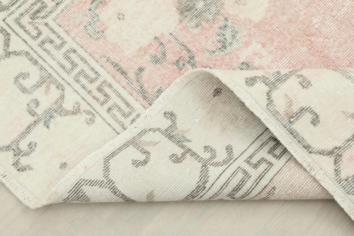 Corner of the rug folded back to show the cotton foundation and the reverse side.