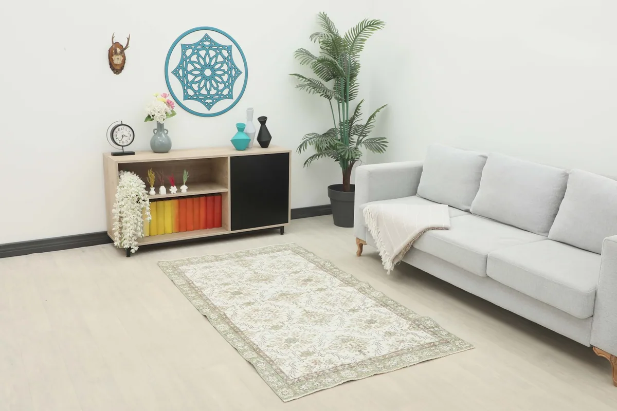 Vintage cream and green rug placed in a modern living room setting with a couch and console table