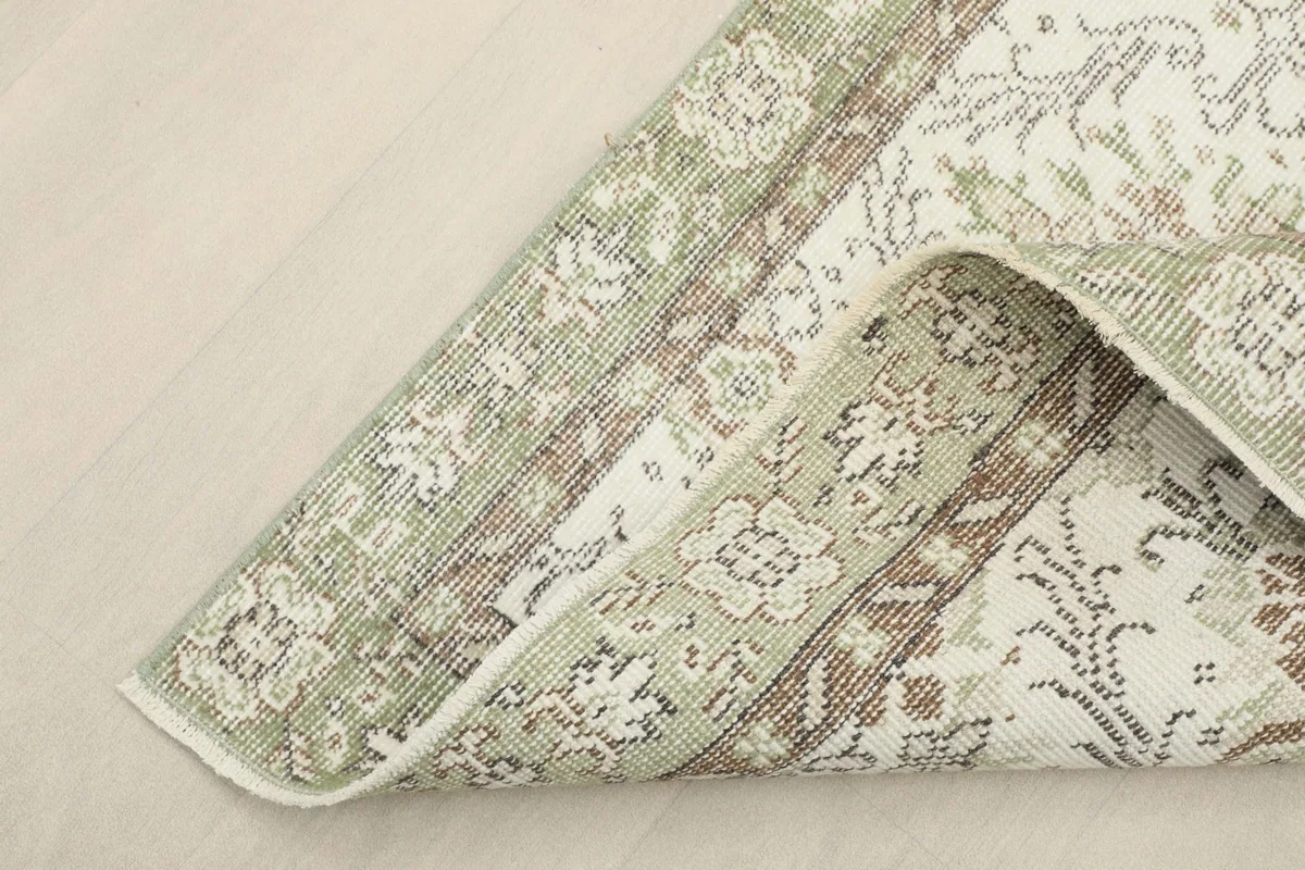 Corner of the rug folded back, showing the cotton foundation and the reverse side of the hand-knotted construction