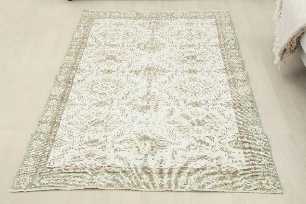 Full overhead view of the cream and green floral Anatolian rug laid flat on a light-colored floor