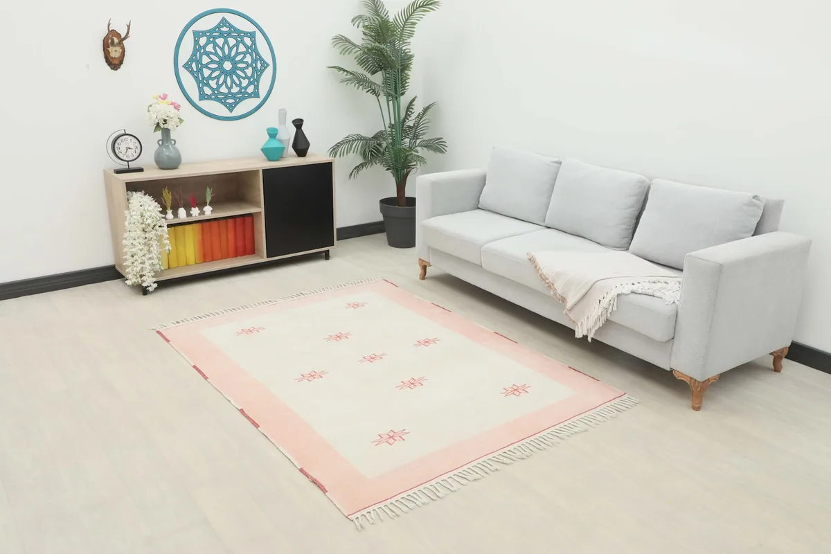Vintage rug displayed in a bright room setting with a sofa and cabinet, showcasing its scale and color.