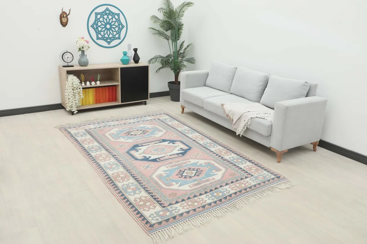 Vintage pink and blue Anatolian rug displayed in a living room setting with a light gray sofa