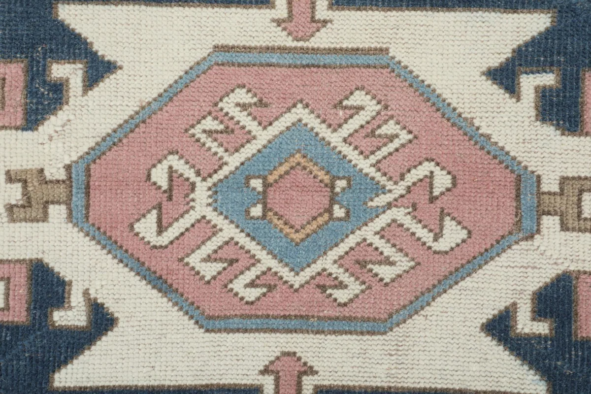 Detailed close-up of a central geometric medallion in navy, blue, and pink on the rug
